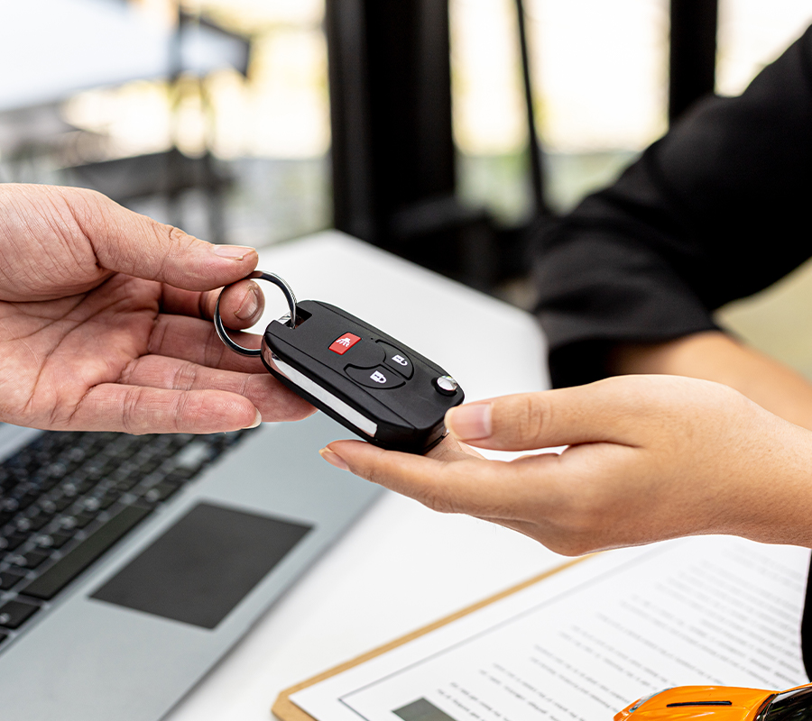 Person returning car keys to car dealership during lease return process