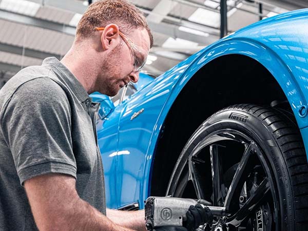 Bentley Service tech putting a tire back on the vehicle