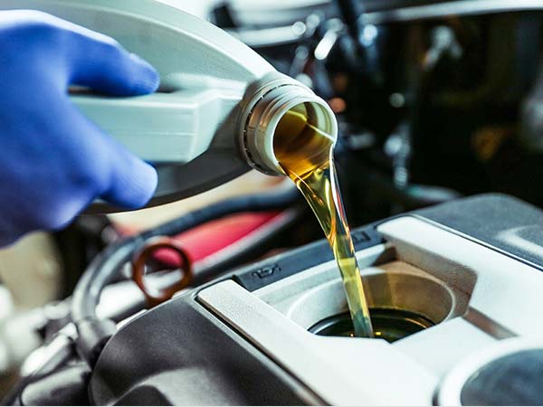 Service tech pouring oil into a vehicle